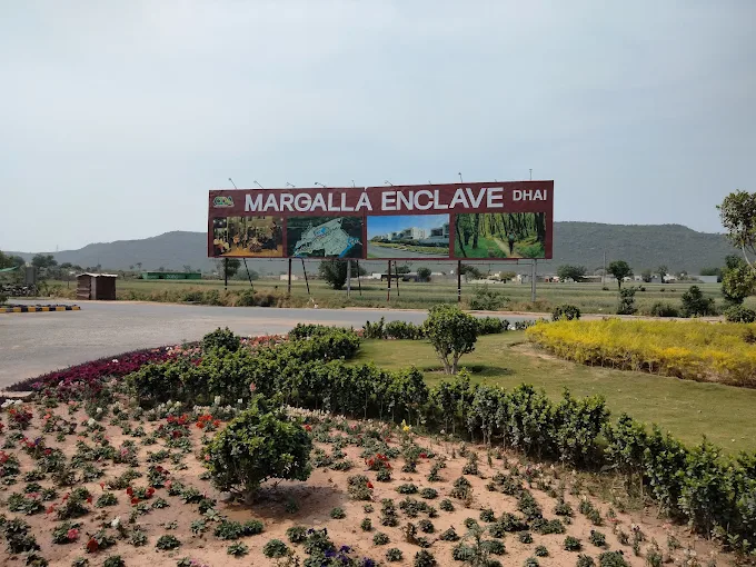 Margalla Enclave DHA Islamabad billboard near Margalla Hills with landscaped gardens and future housing project visuals